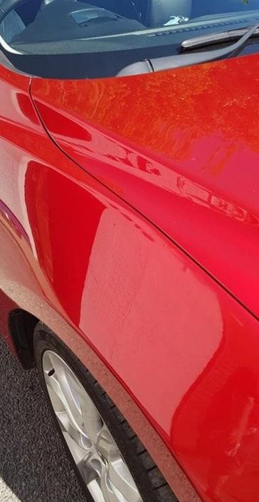Red front wing after accident repair, refinished to a gloss shine